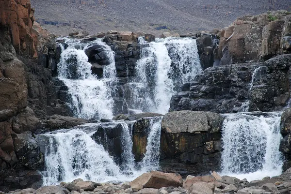 Un paisaje rocoso con una cascada . — Foto de Stock