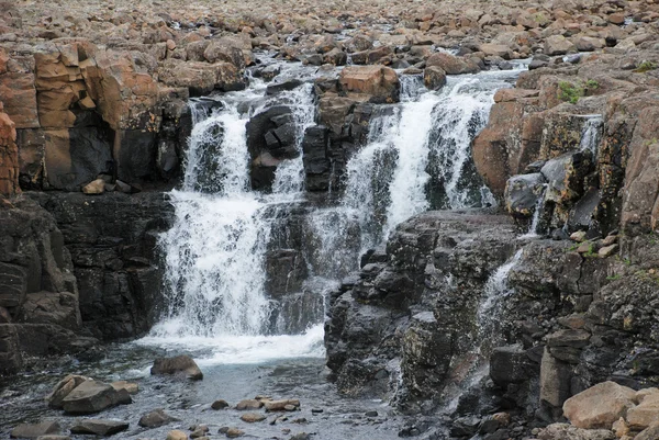 Un paisaje rocoso con una cascada . — Foto de Stock