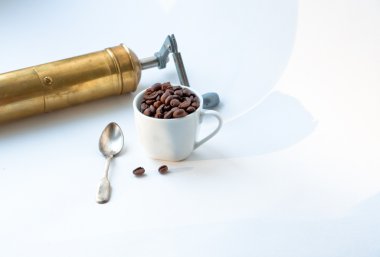 fincan, kahve çekirdeği ve bakır el değirmeni.