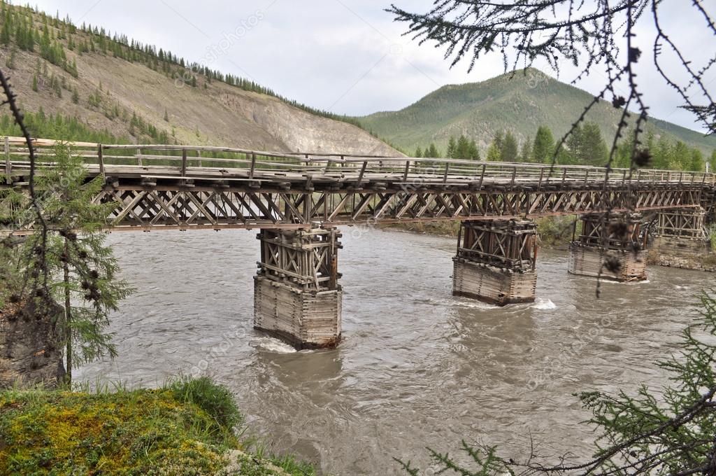 Wooden bridge in Yakutia across the mountain river.
