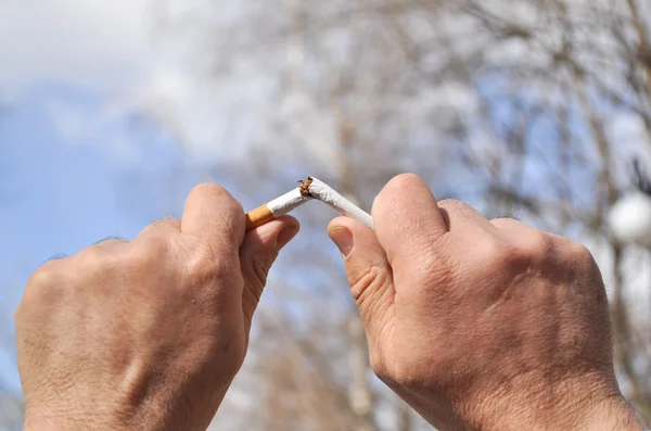Un cigarrillo roto en su mano. — Foto de Stock