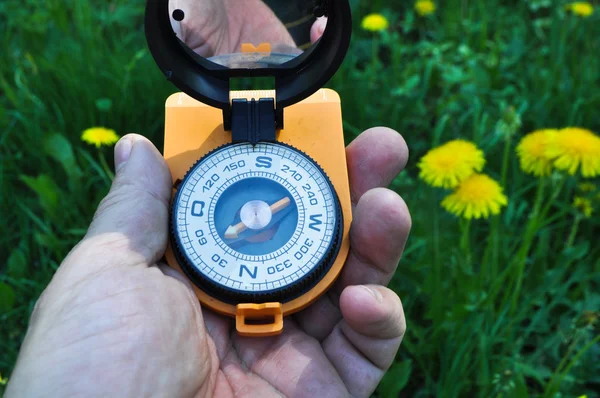Compass in hand, against the background of blooming meadows. — Stock Photo, Image