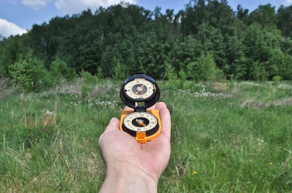 Kompass in der Hand, vor dem Hintergrund des Waldes. — Stockfoto