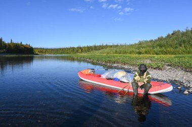 Kuzey Urallar 'da tekne gezisi. Yaz nehri manzarası ve şişme kano..