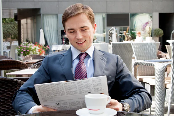Empresario leyendo un periódico en un café y noticias felices —  Fotos de Stock