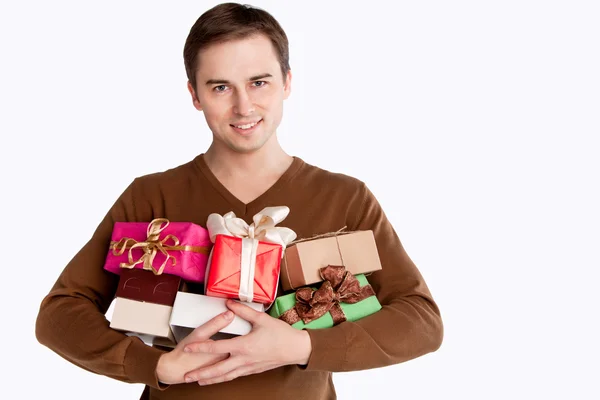 Joven hombre alegre sosteniendo muchos regalos — Foto de Stock