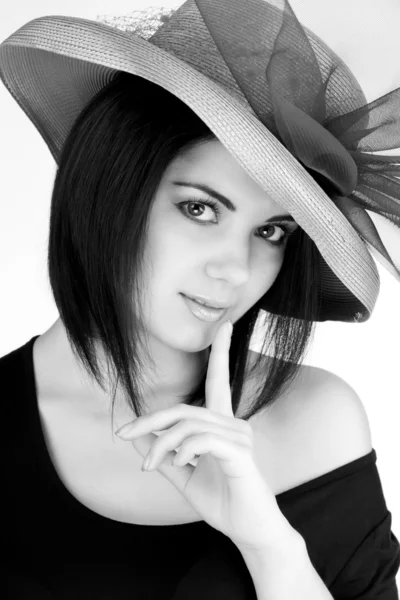 Black and white portrait of a girl in a hat with his finger to his lips — Stock Photo, Image