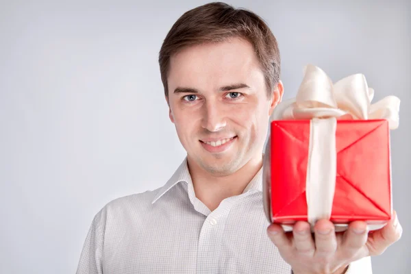 Homem segurando uma caixa com um presente na frente de um close-up — Fotografia de Stock