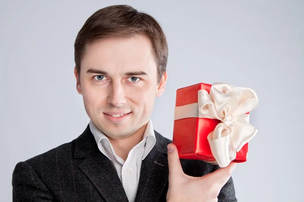 Man houden een geschenk in de buurt van het gezicht, kijk intriruyuschy Stockfoto
