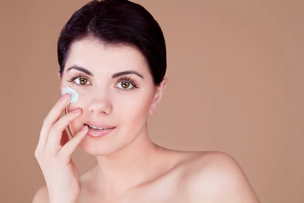 Girl with cream on her cheek smiling biting her finger — Stock Photo, Image