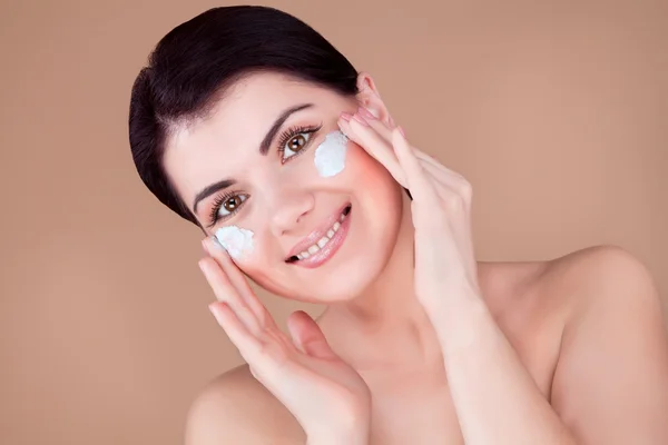 Girl with cream on her cheeks tilted her head, hands near face — Stock Photo, Image