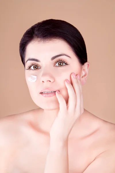 Ragazza con crema sulla guancia tiene una mano vicino al viso — Foto Stock