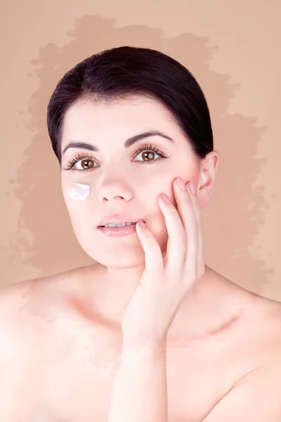 Girl with cream on her cheek holds a hand near the face(unusual toning ) — Stock Photo, Image