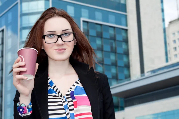 Fille tenant un café dans la rue et sur le fond du bâtiment Image En Vente