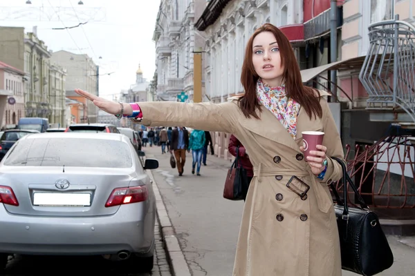 Κορίτσι σε παλτό και πιάνει ένα ταξί kofem Φωτογραφία Αρχείου