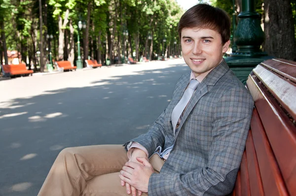 Geschäftsmann sitzt auf einer Parkbank, ruht sich aus, lächelt — Stockfoto