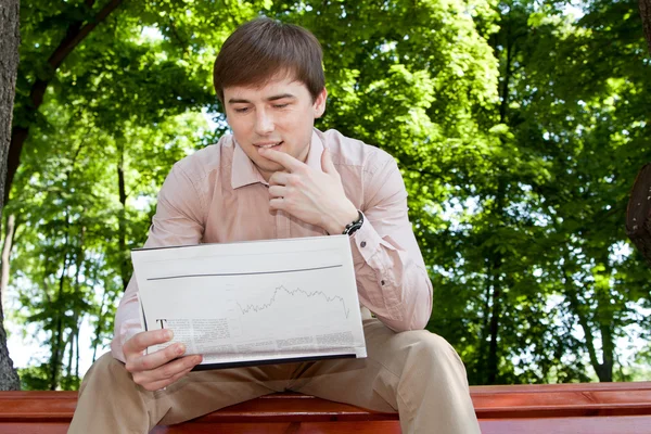 Empresário lendo um jornal em um banco no parque — Fotografia de Stock