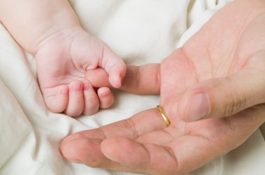 Bebek el bir adamın elini tutarak