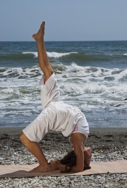 Kadın plajda yoga yapıyor.