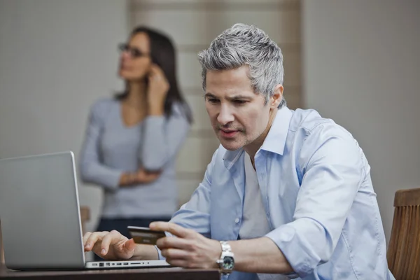 Man doen online winkelen met zijn vrouw praten op een mobiele phon — Stockfoto