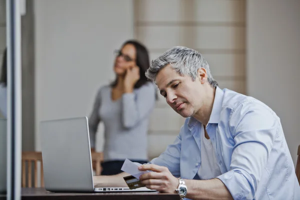 Man doen online winkelen met zijn vrouw praten op een mobiele telefoon — Stockfoto