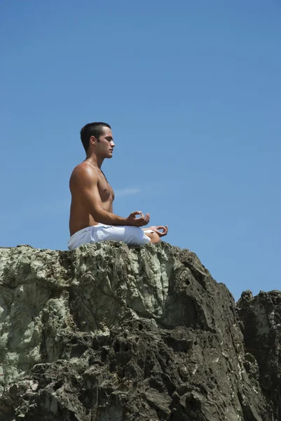 Homme pratiquant le yoga sur un rocher Photo De Stock