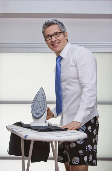 Retrato de un hombre de negocios sonriendo mientras plancha pantalones — Foto de Stock