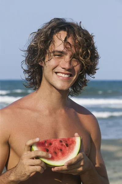 Porträt eines Mannes, der eine Scheibe Wassermelone hält und lächelt — Stockfoto