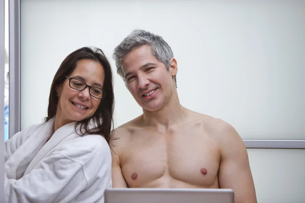 Couple utilisant un ordinateur portable et souriant à la maison Images De Stock Libres De Droits