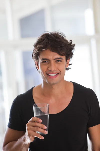 Porträt eines glücklichen jungen Mannes mit einem Glas Wasser — Stockfoto