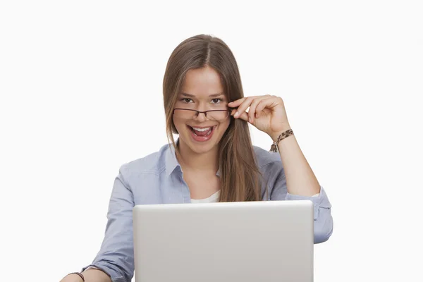 Mujer mirando por encima de las gafas mientras trabaja en un ordenador portátil — Foto de Stock