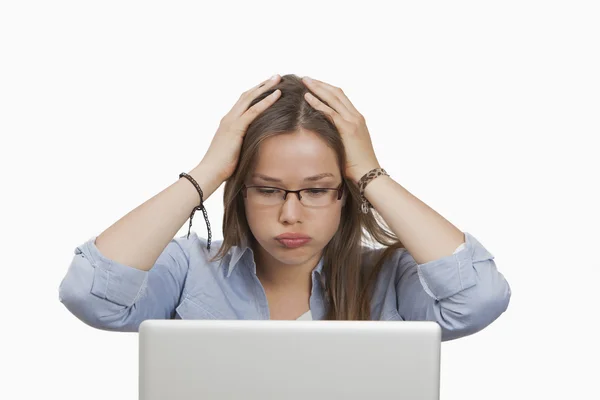 Женщина выглядит обеспокоенной, когда работает над ноутбуком — стоковое фото