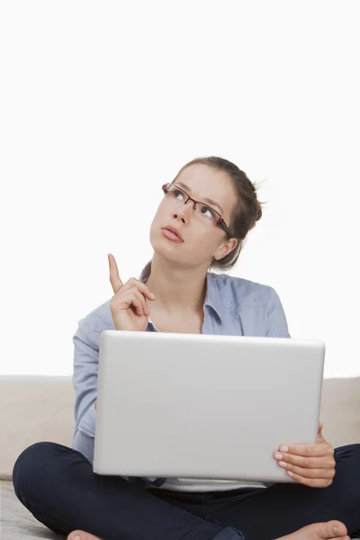 Женщина думает во время работы над ноутбуком — стоковое фото