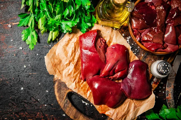 Pieces of raw liver with spices, oil and herbs. Against a dark background. High quality photo