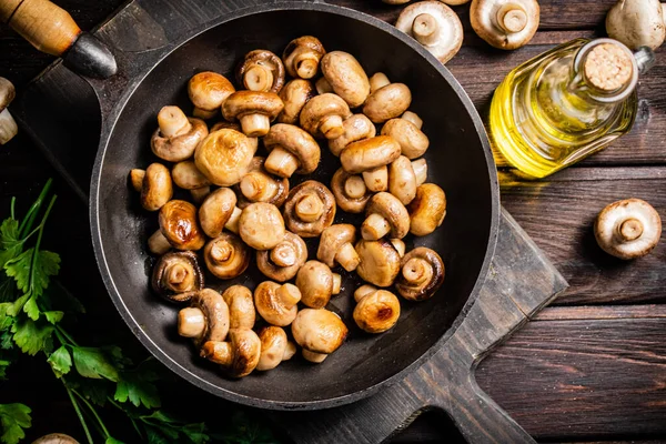 Fragrant homemade fried mushrooms in a frying pan on a cutting board. On a wooden background. High quality photo