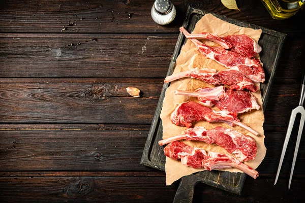 Raw rack of lamb on a spice cutting board. On a wooden background. High quality photo