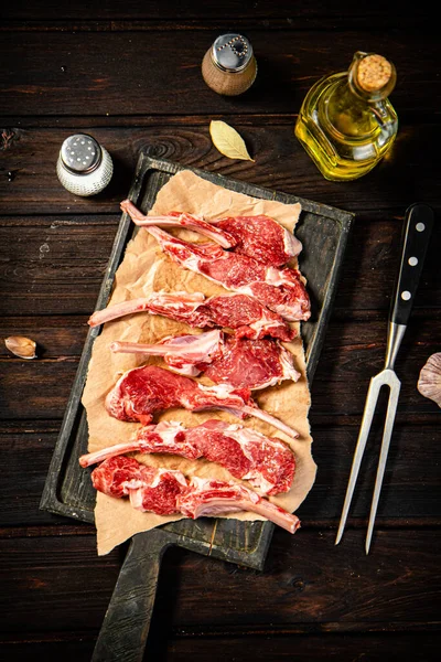 Raw rack of lamb on a spice cutting board. On a wooden background. High quality photo