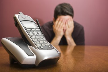 Man hides his face waiting for the phone to ring clipart