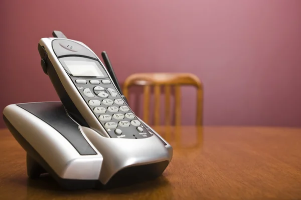 Draadloze telefoon op een tafel met stoel Rechtenvrije Stockafbeeldingen