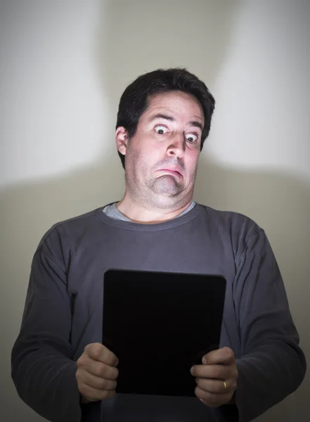 L'homme est horrifié par ce qu'il voit sur une tablette numérique — Photo