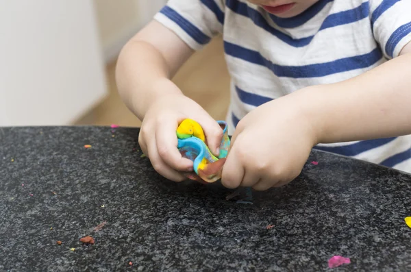 Toddler playing with multicoloured playdough — Stock Photo, Image