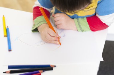 genç çocuk turuncu bir kalemle çizer