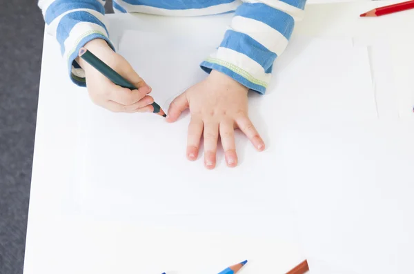 Niño traza el contorno de su mano con un lápiz — Foto de Stock