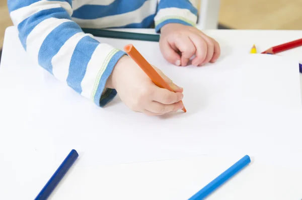Toddler draws with an orange pencil — Stock Photo, Image