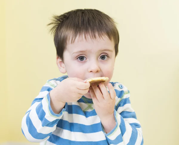 Ung pojke som äter en pikelet — Stockfoto