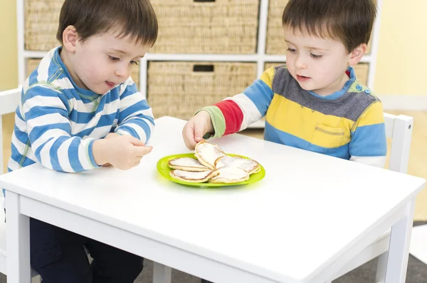 Twin boys eating pikelets — Stock Photo, Image