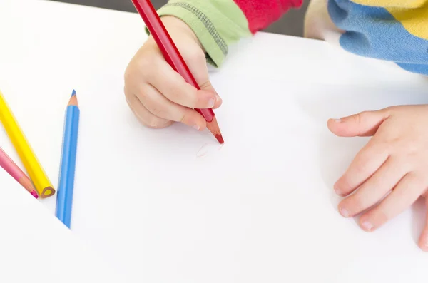 Young boy draws with a red pencil — Stock Photo, Image