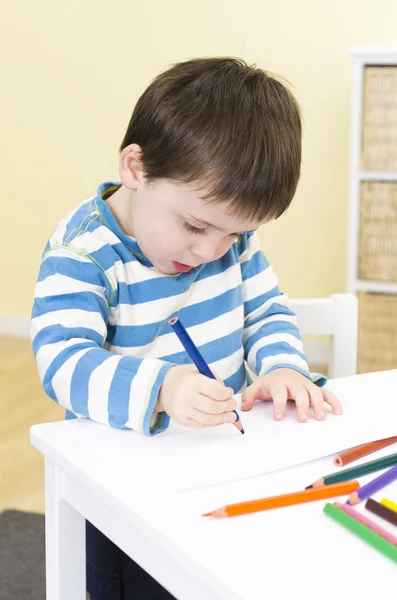 Young boy draws with a blue pencil — Stock Photo, Image