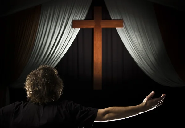 Young man prays before a cross — Stock Photo, Image