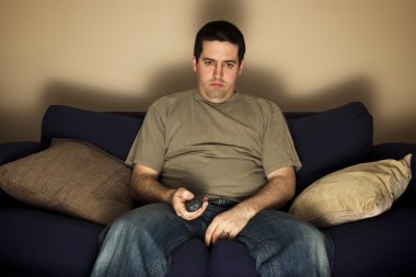 Bored, overweight man sits on the sofa clipart